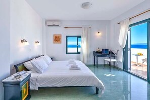 Habitación de hotel con cama, escritorio, silla y vista al mar.