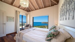 Ein Schlafzimmer mit einem großen Bett, Meerblick und Holzboden.