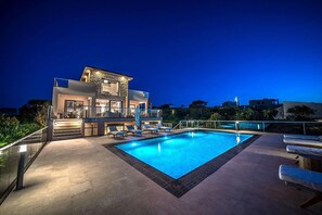 A modern hotel with a swimming pool, a covered terrace, and a view of the surrounding area.