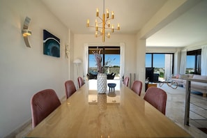 A modern dining room with a large wooden table, red chairs, and a unique chandelier.