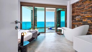 Quarto de hotel moderno com uma grande porta de correr de vidro que dá para uma varanda com vista para o mar.