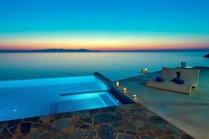 A infinity pool with a view of the sea and a lounge area with cushions and candles. - Seafront Villa VIP with a heated pool (Tersanas)
