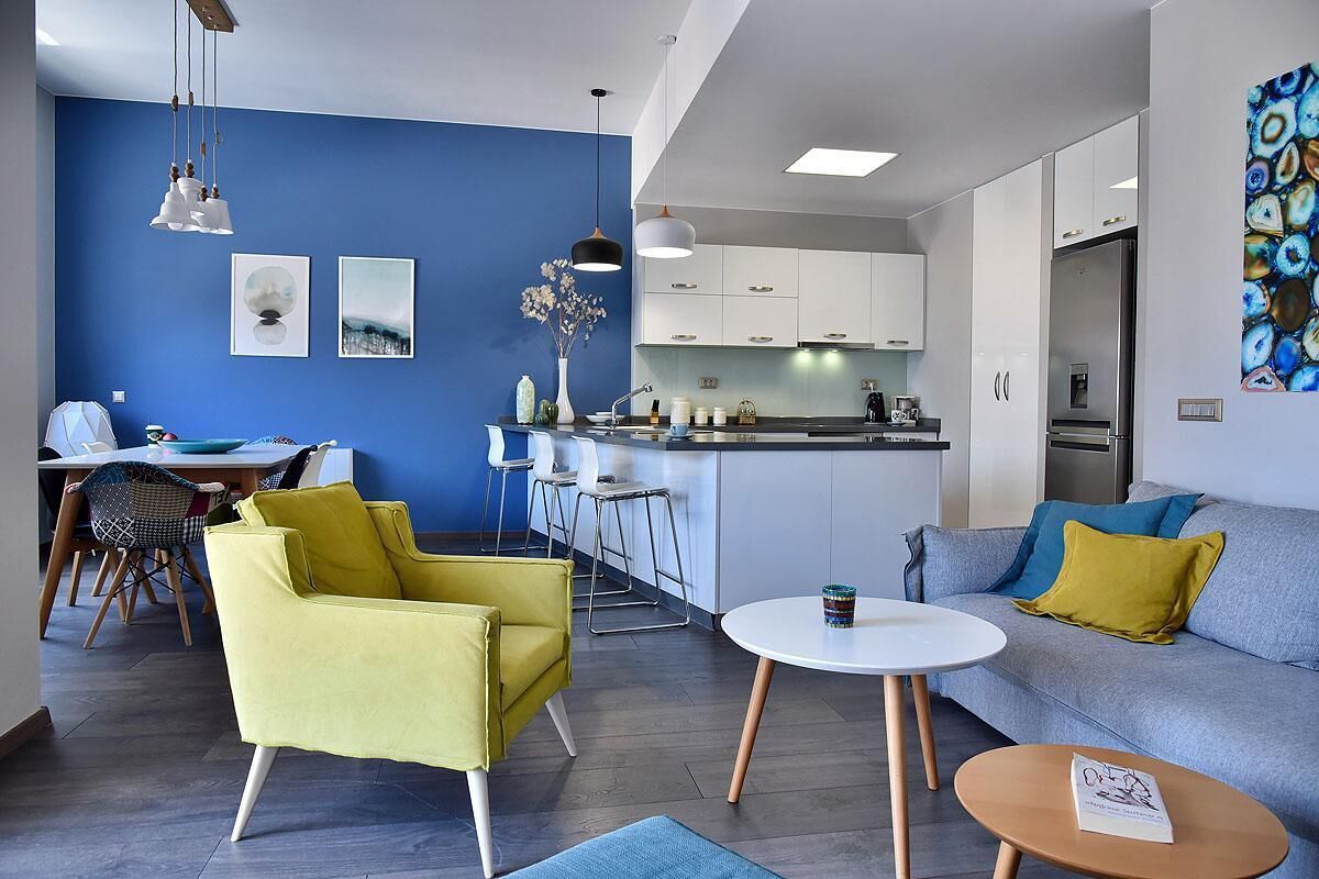 A modern living space with a blue accent wall, a kitchen area, and a dining setup.
