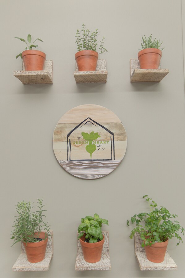 Una pared con cinco macetas de terracota y una placa de madera con diseño de casa y corazón.