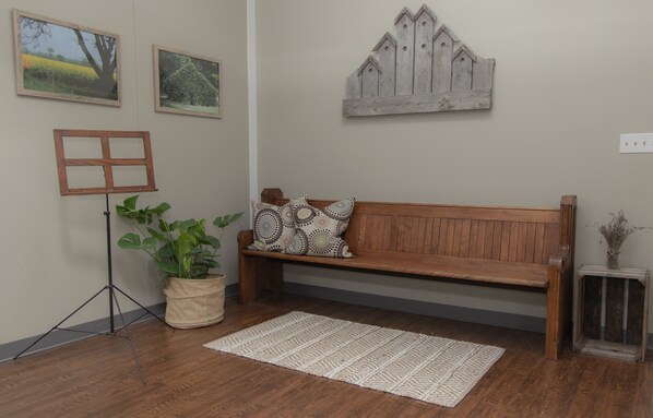A wooden bench with patterned cushions, a potted plant, and a rustic wall decoration.