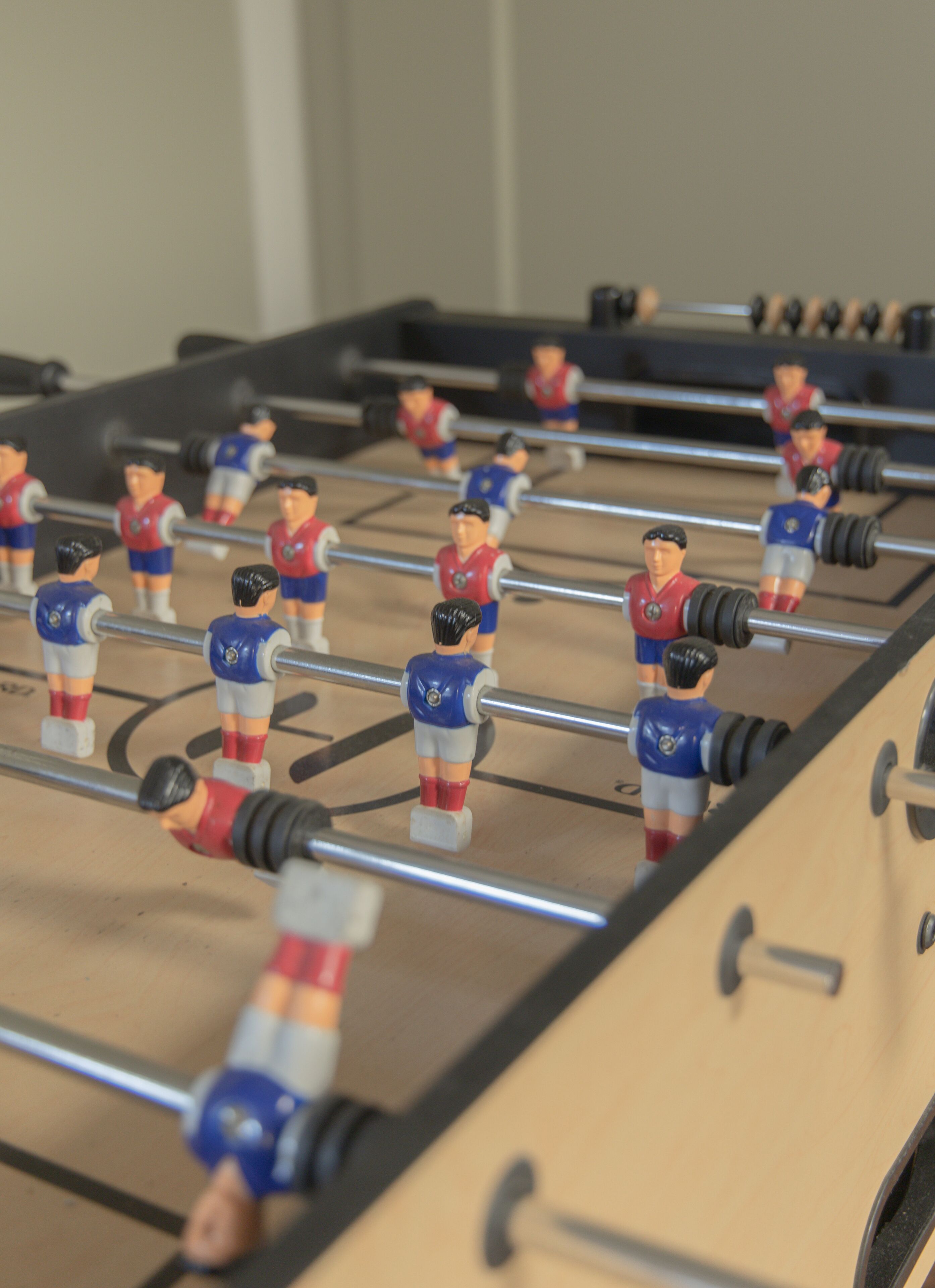 A foosball table with multiple players in red and blue uniforms.
