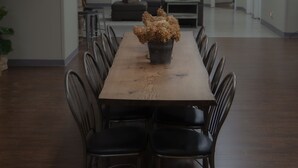 Een vergaderruimte met een lange houten tafel, zwarte stoelen en een bloempot als decoratie.