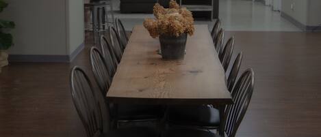 A conference room with a long wooden table, black chairs, and a potted plant centerpiece.