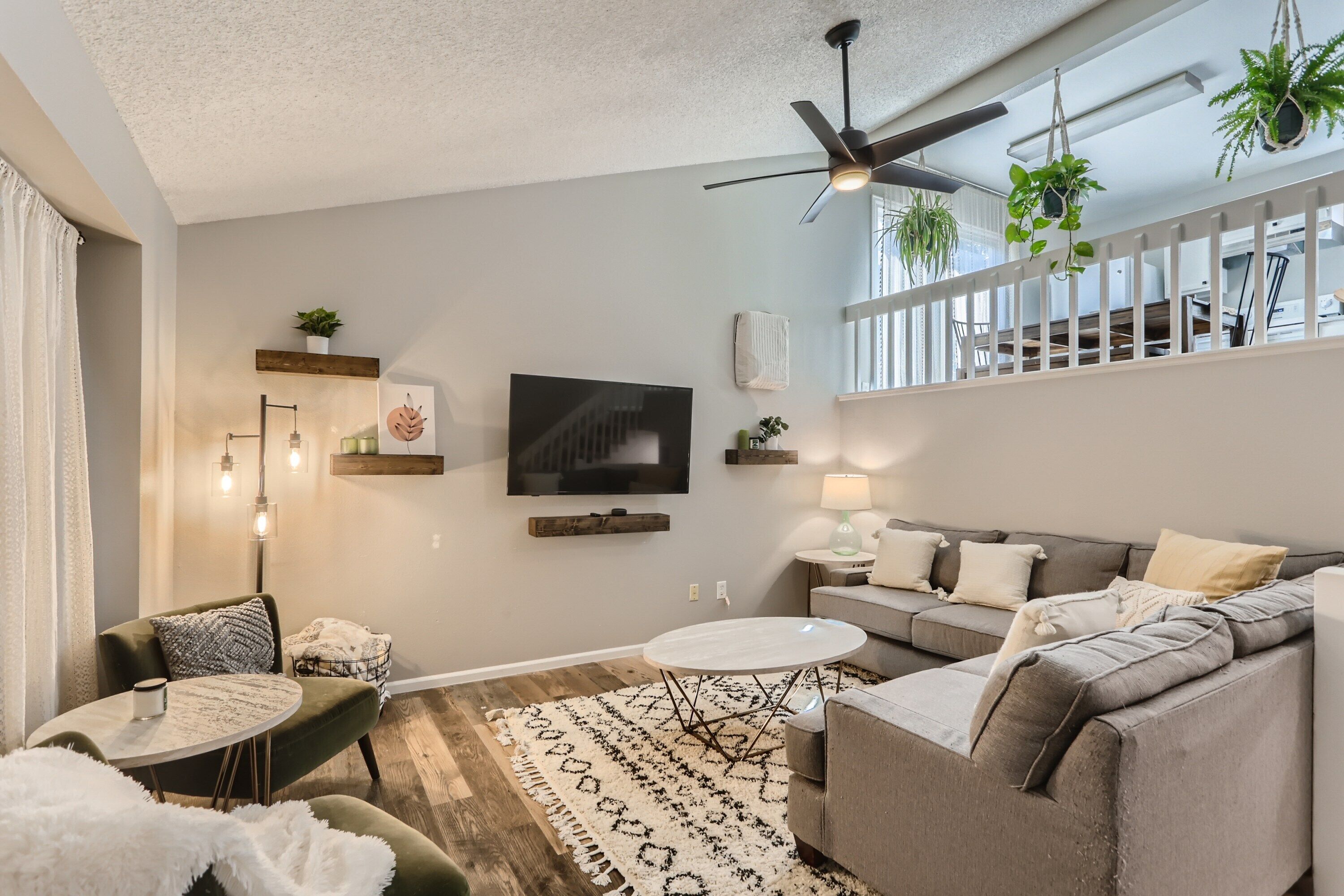 A modern living room with a grey sofa, a round coffee table, and a ceiling fan.