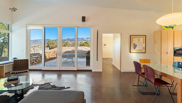 Ein modernes Interieur mit Essbereich, einer Küche und Blick auf eine Berglandschaft durch große Schiebetüren.