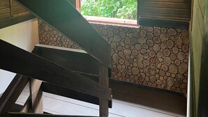 Portaat johtavat huoneeseen, jossa on ikkuna, josta avautuu näkymä vehreään maisemaan. Huoneessa on lisäksi puisia kattopalkkeja ja kiviseinä.
