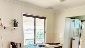 Una cocina moderna con una isla central, horno integrado y ventana con vistas a un balcón.