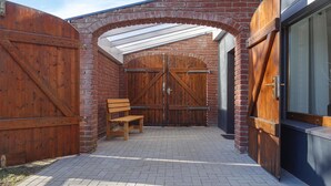 A covered outdoor area with a brick wall, wooden gates, and a bench. - 2 bedroom amazing apartment in Loxstedt (Loxstedt)