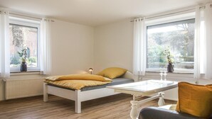 A bedroom with a bed, a bedside table, a window with curtains, a radiator, and a view of the outside. - 2 bedroom amazing apartment in Loxstedt (Loxstedt)