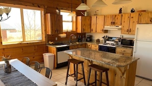 Una cocina con armarios de madera, encimera de granito y una isla central con taburetes.