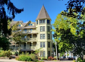 A multi-story building with a prominent tower, balconies, and a well-maintained garden.