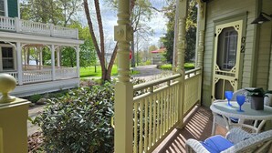 Une véranda avec une balustrade blanche, une petite table avec des coussins bleus et une plante en pot.