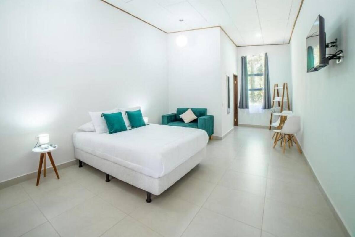 A modern bedroom with a large bed, a small table, and a chair.