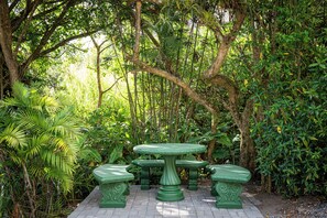 A garden setting with a green table and benches surrounded by lush foliage. - Natüra Hotel Monteverde (Monteverde)