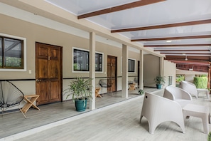 A covered outdoor area with wooden doors, potted plants, and wicker furniture. - Natüra Hotel Monteverde (Monteverde)