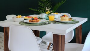 Una mesa de comedor con sillas, un reloj en la pared y una planta al fondo.