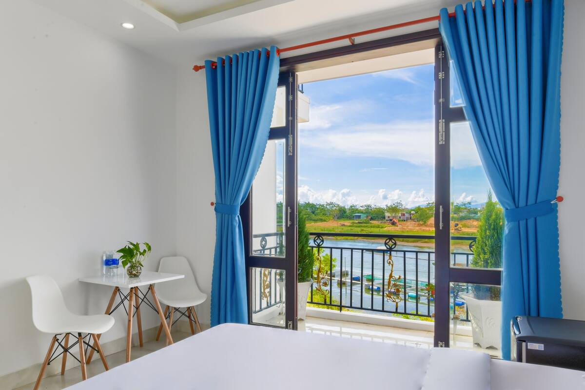 A hotel room with a balcony, white furniture, and a view of a body of water.