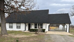 A single-story house with a dark roof and white exterior walls, a front porch, and a covered driveway.