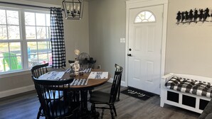 A dining area with a wooden table, black chairs, a chandelier, and a white door with a decorative window.