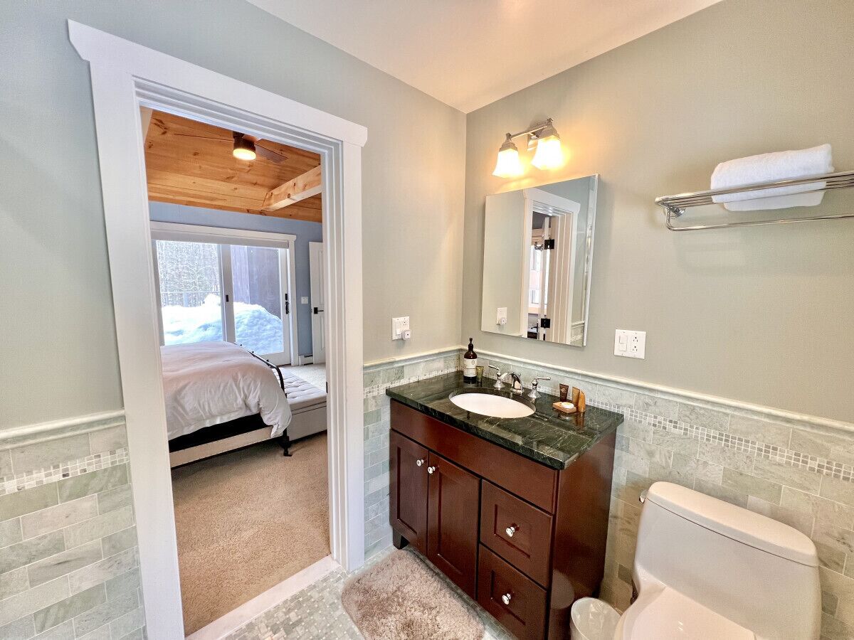 A bathroom with a wooden ceiling, a sink, a toilet, and a mirror.
