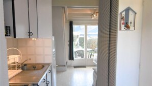 A narrow hallway with a kitchen area on one side, featuring a sink, stove, and cabinets. - Maisonette 3 rooms 4 people 50 m from the port of St Jacques (SARZEAU)