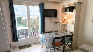 A room with a dining table, chairs, a TV mounted on the wall, a bed, and a small balcony with chairs. - Maisonette 3 rooms 4 people 50 m from the port of St Jacques (SARZEAU)