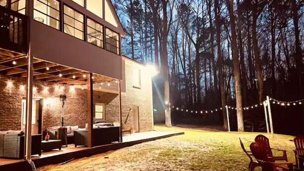 A modern house with a large deck, outdoor seating, and string lights. - Cozy and charming private home on an acre lot (Duluth)