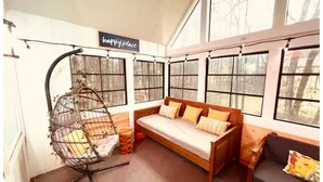 A cozy room with a wooden sofa, a hanging chair, and a 'happy place' sign. - Cozy and charming private home on an acre lot (Duluth)