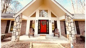 A house with a stone facade, a red door, and a porch with two chairs. - Cozy and charming private home on an acre lot (Duluth)