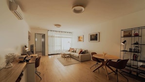 Un salon moderne avec un canapé, une table basse et une table à manger. On y trouve également une bibliothèque et un bureau avec un ordinateur.