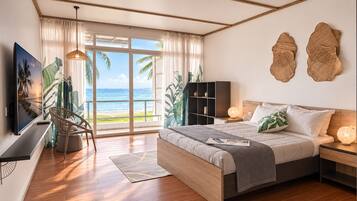 Un dormitorio con una cama grande, televisor, estantería y vista al océano.