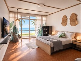 Un dormitorio con una cama grande, televisor, estantería y vista al océano.
