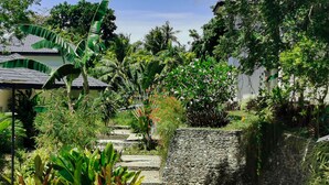 A garden pathway with stone steps surrounded by lush greenery and various plants. - Blue Joys Marine Sports Resort (San Juan)