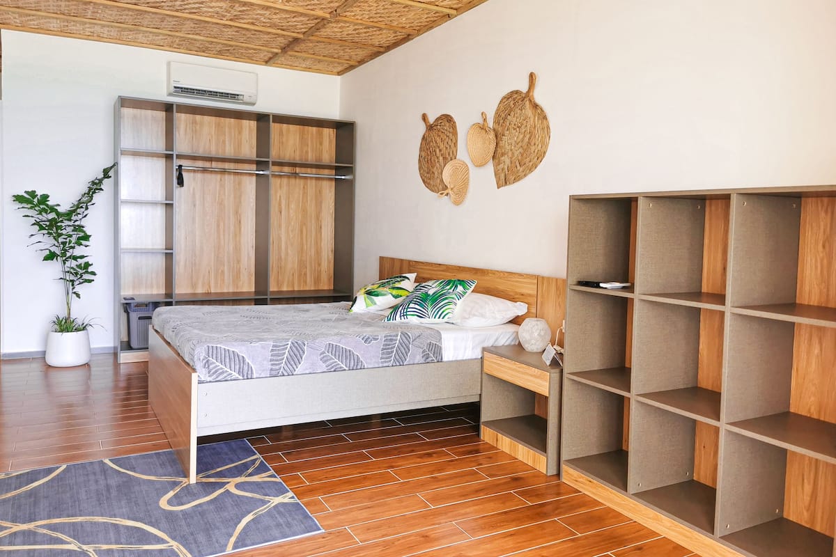 Ein modernes Schlafzimmer mit einem hölzernen Bett, integriertem Kleiderschrank und einer Topfpflanze.