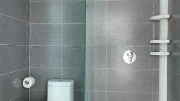 A modern bathroom with grey tiles, a white toilet, a glass shower enclosure, and a wooden floor.