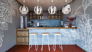 Zona de bar con taburetes de madera, una barra y decoración mural.