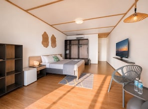 A modern bedroom with a bed, bedside tables, a wardrobe, a television, and a chair. - Blue Joys Marine Sports Resort (San Juan)