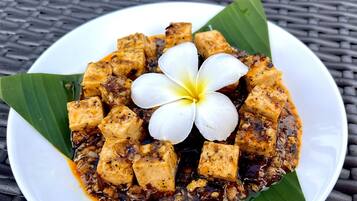 Un piatto di tofu guarnito con un fiore su un tavolo intrecciato.