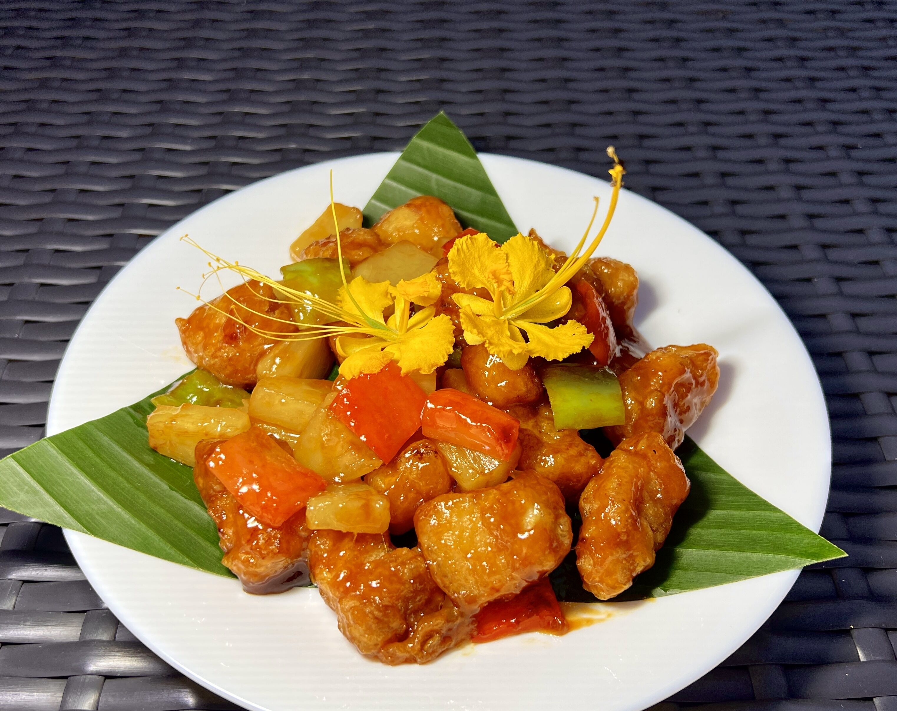 Prato de comida com legumes e carne, decorado com flores amarelas.