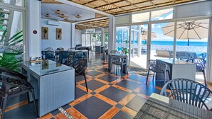 A restaurant with outdoor seating, a thatched ceiling, and a view of the sea. - Blue Joys Marine Sports Resort (San Juan)