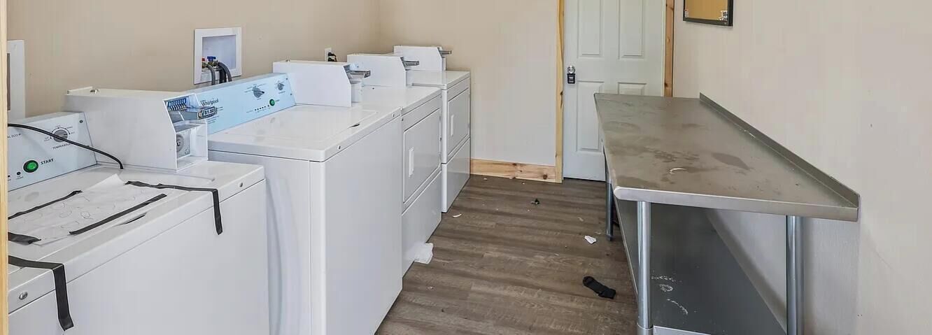 A laundry area with multiple washing machines and a metal table.