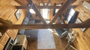 A high-ceilinged wooden cabin interior with a kitchen area, seating, and a visible window. - Cozy cabin with views of Lake Erie and colorful sunsets! (Ashtabula)