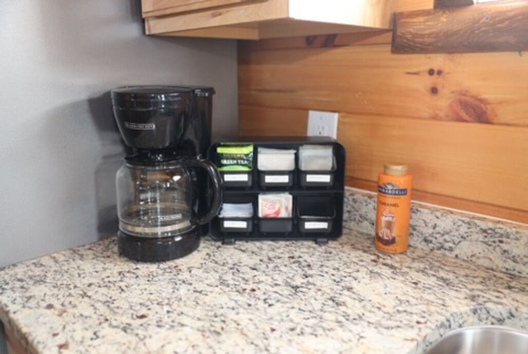 A kitchen counter with a coffee maker, a tea infuser, and a canister.