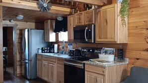 A rustic kitchen with wooden cabinets, stainless steel appliances, and a farmhouse sink. - Cozy cabin with views of Lake Erie and colorful sunsets! (Ashtabula)