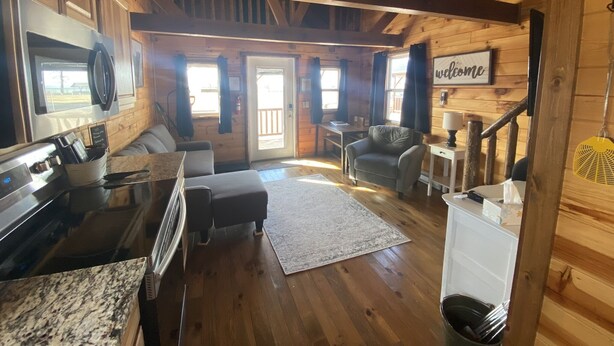 A cozy cabin interior with a kitchen, seating area, and a staircase. - Cozy cabin with views of Lake Erie and colorful sunsets! (Ashtabula)